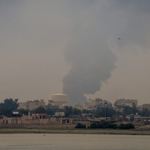 A plume of smoke rises after a reported Iranian strike on fuel tanks in Muharraq on March 12, 2026. Oil soared above $100 and stocks sank on March 12 as Iran's fresh attempts to hit supplies in the Middle East and threats to bring down the global economy overshadowed a record release of strategic crude by the International Energy Agency. Bahrain reported Iran had carried out an attack on fuel tanks in the country, while Saudi Arabia said it had intercepted drones headed to Shaybah oil field and drones struck fuel tanks at Oman's Salalah port, where operations were subsequently suspended. (Photo by Fadhel MADHAN / AFP) /