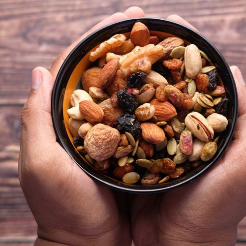 Hand holding a bowl of mixed nut top down.