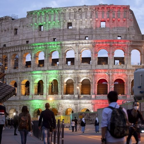 epa08456604 People walk in front of the Colosseum on which the colors of the Italian flag are projected during Phase 2 of the emergency Covid-19, Rome, Italy, 31 May 2020. The Colosseum reopens tomorrow, after the lockdown, with a dedicated medical service. The service will be activated for visitors who will be feverish at the control with the thermoscanners installed at access. In addition to the staff of the Park of the Colosseum, the assistance of medical and nursing staff will also be guaranteed.  EPA/MASSIMO PERCOSSI