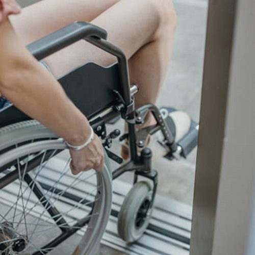 Close-up shot of unrecognizable young woman in wheelchair entering the elevator