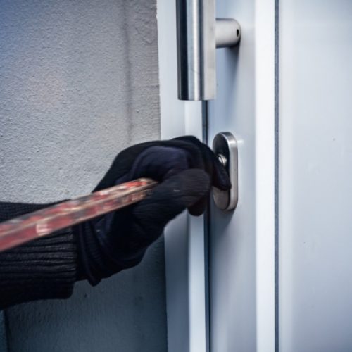 masked burglar with crowbar breaking and entering into a victim's home. motion blur selective focus
