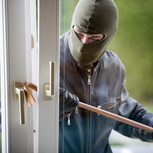 Einbrecher dringt in ein Haus ein.