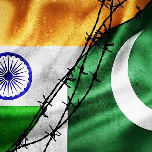 Grunge flags of India and Pakistan divided by barb wire illustration, concept of tense relations between India and Pakistan