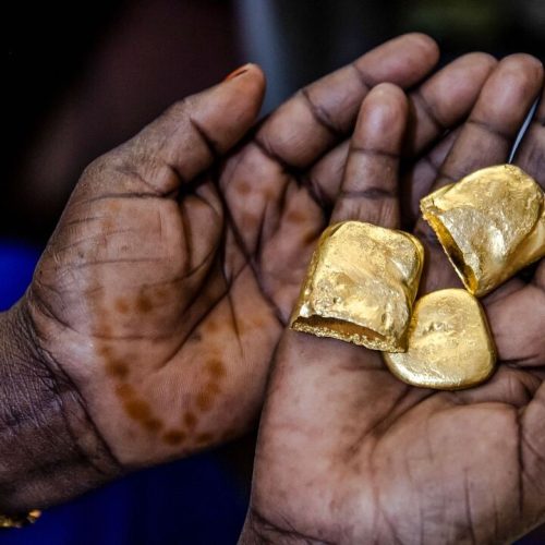 Tanzanian miner Assia Hussein, who is the chairman of an only-women miners association, observes some pure gold nuggets at a gold market in Geita, Tanzania on May 28, 2022. - Tanzania is a land rich in minerals and one of the main gold producers in Africa, with gold representing more than 90% of the country's mineral exports. Artisanal and small-scale gold mining have culturally and historically relegated women's participation. The extractive sector in Tanzania has historically been a male-dominated industry with high levels of harassment, sexual abuse, discrimination and misconceptions over women's involvement, and contributions following traditional beliefs. A a result women face economic challenges due to lack of access to the land. Through the creation only-women miners associations and the help of projects advocating for rights and inclusion in the extractive industry such as the Collective Action For Rights Realisation In Extractives Industry (CLARITY), Tanzanian women in Geita region have been gradually gaining access to the mines while being able to benefit from the sector. (Photo by LUIS TATO / AFP) (Photo by LUIS TATO/AFP via Getty Images)