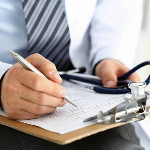 Male medicine doctor hand holding silver pen writing something on clipboard closeup. Ward round, patient visit check, medical calculation and statistics concept. Physician ready to examine patient