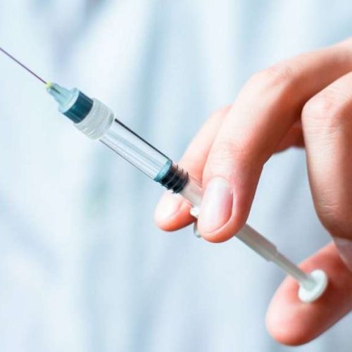 Syringe, medical injection in hand, palm or fingers. Medicine plastic vaccination equipment with needle. Nurse or doctor. Liquid drug or narcotic. Health care in hospital.