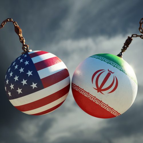 Wrecking balls textured with American and Iranian flags over dark stormy sky. Horizontal composition with copy space and selective focus. Dispute concept.