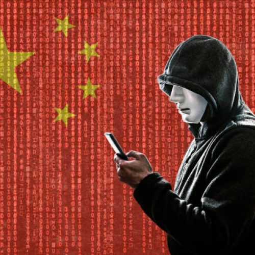 Chinese hooded hacker with mask holding smartphone