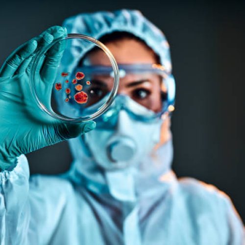 Selective focus of biochemist taking biomaterial from petri dish with tweezers.