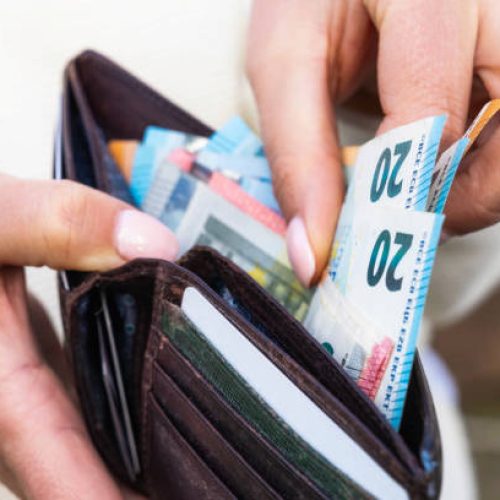 Macro image as a woman takes Euro banknotes from a leather wallet.