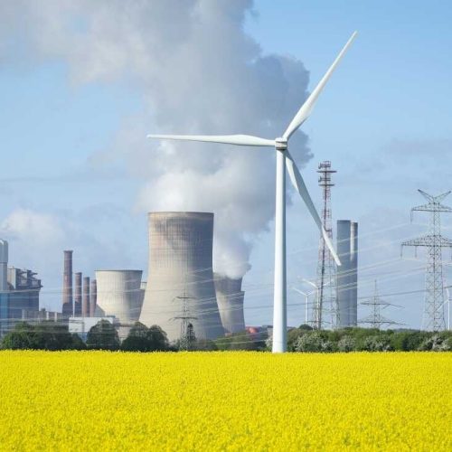 INGENDORF, GERMANY - APRIL 15: Wind turbines stand next to a yellow blossoming rape field as water vapour rises from the cooling towers of the Neurath coal-fired power plant on April 15, 2024 in Ingendorf near Rommerskirchen, Germany. The German government has significantly increased the expansion paths and tender volumes for renewable energies such as solar and wind energy. Planning and authorisation procedures are being simplified. The expansion of renewable energies is gaining significant momentum. Germany is on a roadmap to shutter all of its coal-fired power production by 2038.  (Photo by Andreas Rentz/Getty Images)