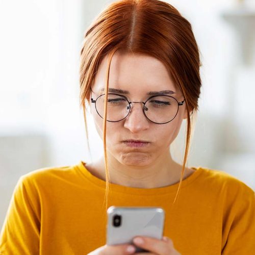 Angry young girl with red hair chatting using a mobile phone